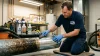 Technicien en bleu nettoie une tuyauterie métallique avec une brosse